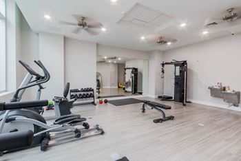 A spacious gym with a variety of equipment including treadmills, weights, and a bench press.